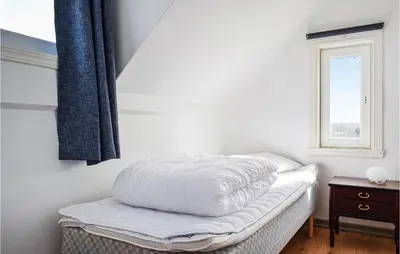 a bed with a white comforter on it in a room at Amazing Home In Torangsvåg With Wifi in Skår