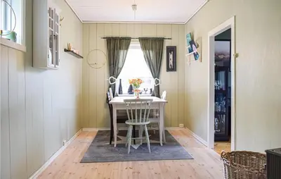 a dining room table with chairs and a window at Beach Front Home In Tysse With Wifi in Tysse