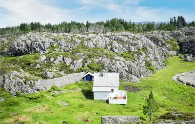 a small white house on a rocky hillside withgrass at 2 Bedroom Cozy Home In Stolmen