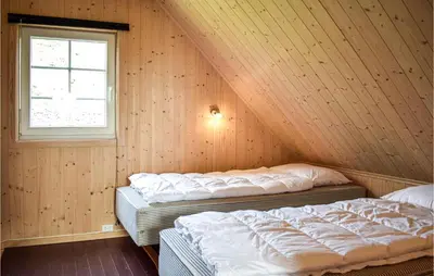 two beds in a wooden room with a window at 2 Bedroom Cozy Home In Stolmen