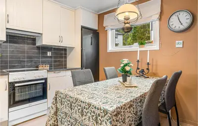 a kitchen with a table with chairs and a clock on the wall at 2 Bedroom Nice Home In Fana in Fanahammaren