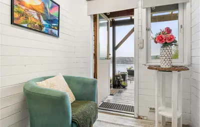 a porch with a green chair and a vase of flowers at 2 Bedroom Nice Home In Fana in Fanahammaren
