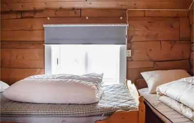 a bedroom with a wooden wall with a bed and a window at Pet Friendly Home In Evanger in Evanger