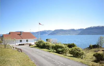 a house on the side of a road next to a lake at 5 Bedroom Beach Front Home In Lavik in Lavik
