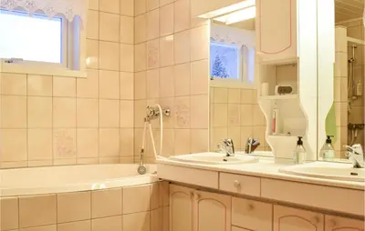 a bathroom with two sinks and a tub and a mirror at 5 Bedroom Beach Front Home In Lavik in Lavik