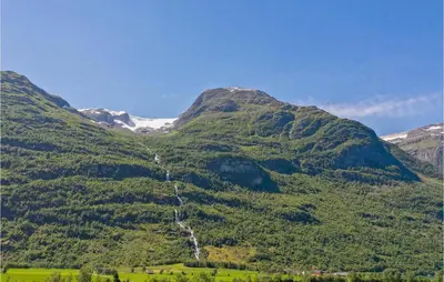 a mountain with green vegetation and snow capped mountains at Awesome Home In Oldedalen in Briksdalsbre