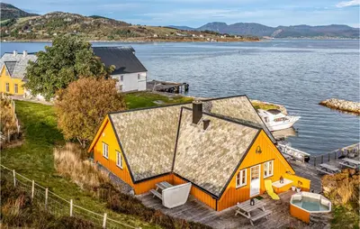 an orange house on the shore of a body of water at Beach Front Home In Kvamsøy in Sandvik