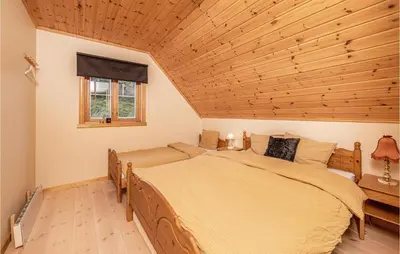 a bedroom with a large bed and a wooden ceiling at Beach Front Home In Kvamsøy in Sandvik