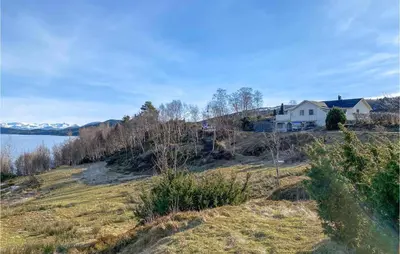 a house on a hill next to a body of water at Lovely Apartment In Ellingsøy in Myklebost