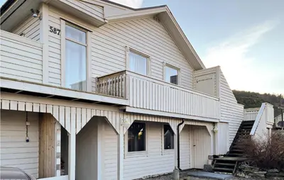 a house with white siding and a balcony at Lovely Apartment In Ellingsøy in Myklebost
