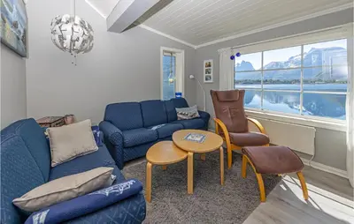 a living room with blue couches and a table and chairs at 2 Bedroom Awesome Home In Isfjorden in Isfjorden