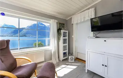 a living room with a tv and a large window at 2 Bedroom Awesome Home In Isfjorden in Isfjorden