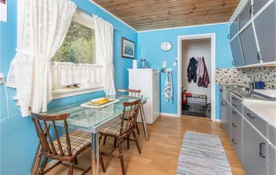 a blue kitchen with a glass table and chairs at 5 Bedroom Pet Friendly Home In Vestnes in Vestnes