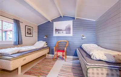 a room with two beds and a chair in it at 2 Bedroom Cozy Home In Øydegard in Nastad