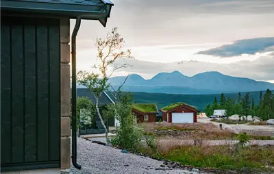a green building with mountains in the background at Beautiful Home In Engerdal With Kitchen in Kvisla