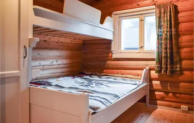 a bed in a log cabin with a window at Nice Home In Kvam With Kitchen in Kvam