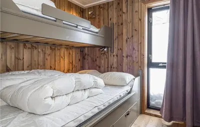 a bed in a room with a wooden wall at 4 Bedroom Lovely Home In Øyer in Øyer