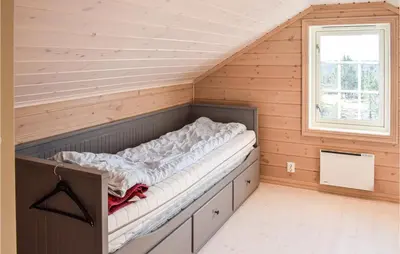 a bed in the corner of a room with a window at 3 Bedroom Amazing Home In Sjusjøen in Sjusjøen