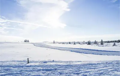 a snow covered field with a road in the distance at Cozy Home In Sjusjøen in Sjusjøen