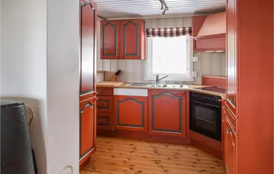a kitchen with red cabinets and a sink and a window at 4 Bedroom Nice Home In Sjusjøen in Sjusjøen