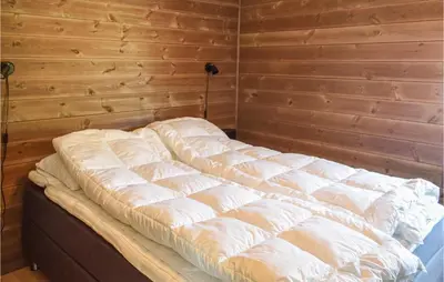 a bed in a room with a wooden wall at 4 Bedroom Cozy Home In Sjusjøen in Sjusjøen