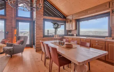 a kitchen with a wooden table and chairs and windows at Nice Home In Reinli With Kitchen in Reinli