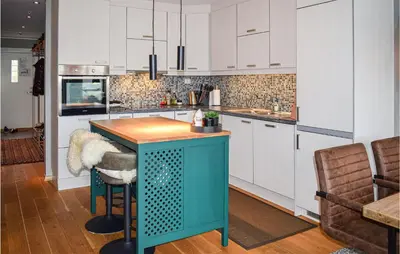 a kitchen with white cabinets and a blue island at 2 Bedroom Cozy Apartment In Geilo in Geilo