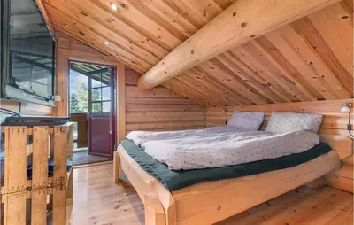 a bedroom with a bed in a log cabin at Gorgeous Home In Lampeland With Kitchen in Lampeland