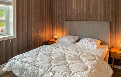 a large bed in a bedroom with wooden walls at Beautiful Home In Rødberg in Rødberg