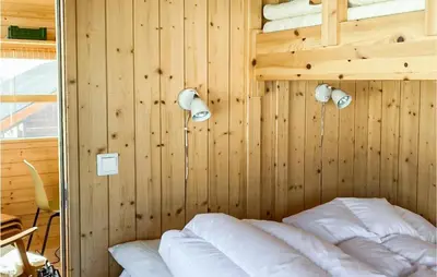 a bedroom with a wooden wall with a bed and lights at 1 Bedroom Nice Home In Geilo in Geilo