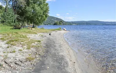 a sandy beach next to a body of water at Bjertnes Turistgård in Noresund