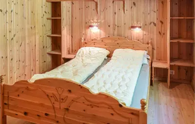 a bed in a room with wooden walls and shelves at Bjertnes Turistgård in Noresund