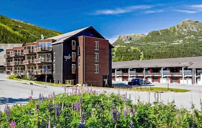 a building with a parking lot in front of a mountain at Cozy Apartment In Hemsedal With Sauna in Hemsedal