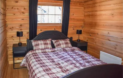 a bed in a room with wooden walls and a window at Cozy Home In Hovden I Setesdal in Hovden