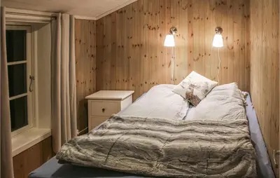 a bedroom with a bed with a wooden wall at Beautiful Home In Hovden I Setesdal in Hovden