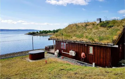a house with a grass roof with the water at Nice Home In Malm With Lake View in Malm