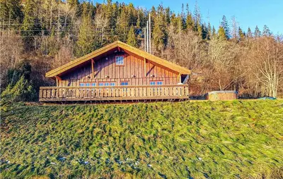 a large wooden cabin on a hill in a field at Nice Home In Malm With Lake View in Malm