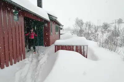 a woman standing next to a building in the snow at Reinunga Eco Hytta - Mountain lodge near Myrdal accessible only by train or bike in Myrdal