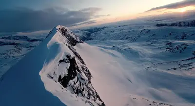 a mountain covered in snow with the sun in the background at Skjolden Resort in Skjolden