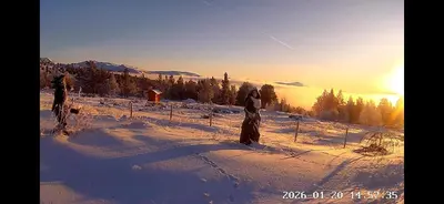 two people standing on a snow covered hill with the sunset at Trollvang, hytte med pool og sauna in Dovreskogen