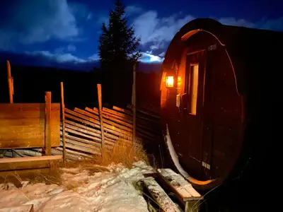 a small cabin with a light in the window at Trollvang, hytte med pool og sauna in Dovreskogen