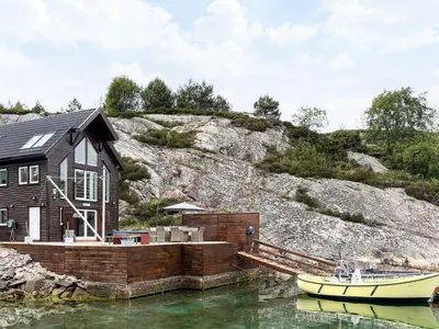 a house on the water with a boat in the water at 6 person holiday home in Urangsvåg-By Traum in Ervik