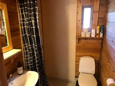 a bathroom with a white toilet and a sink at Solvang World Heritage Camping in Eidsdal