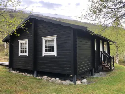 a black house with white windows on a grass field at Solvang World Heritage Camping in Eidsdal