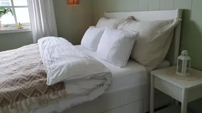 a bed with white sheets and pillows on it at Trygheim feriehus in Bud