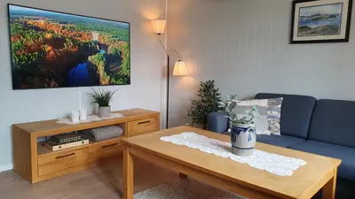 a living room with a blue couch and a table at Trygheim feriehus in Bud