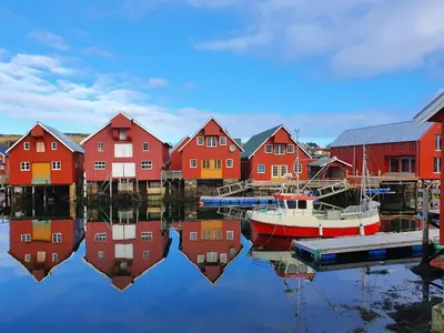 a group of red houses and a boat in the water at Trygheim feriehus in Bud