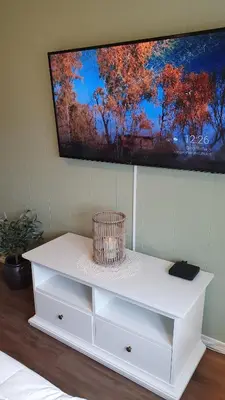 a white cabinet with a television on a wall at Trygheim feriehus in Bud