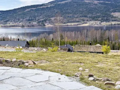 a field of grass with a house and a lake at 8 person holiday home in HURDAL-By Traum in Hurdal