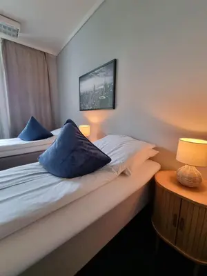two beds in a small room with two lamps at A11 Apartments in Ålesund